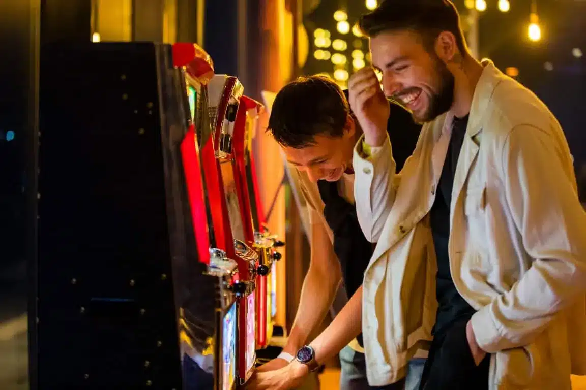 Twee gasten lachen bij een fruitmachine op een feest