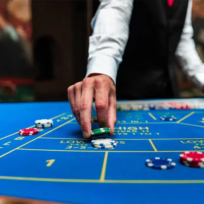 Croupier plaatst een fiche op het chuck-a-luck speelveld